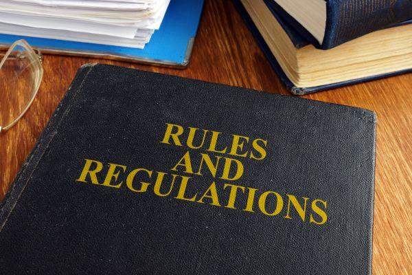 A rules and regulations book resting on a desk, with a pen nearby for notes.
