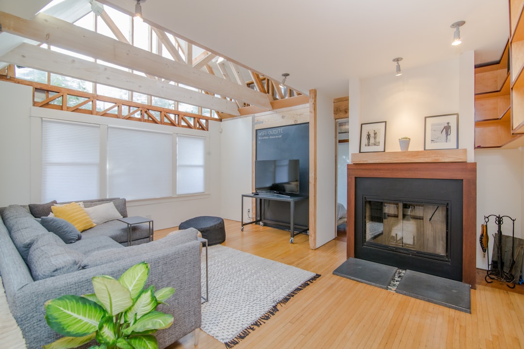 Modern living room with vaulted ceiling, exposed beams, fireplace, and large windows.
