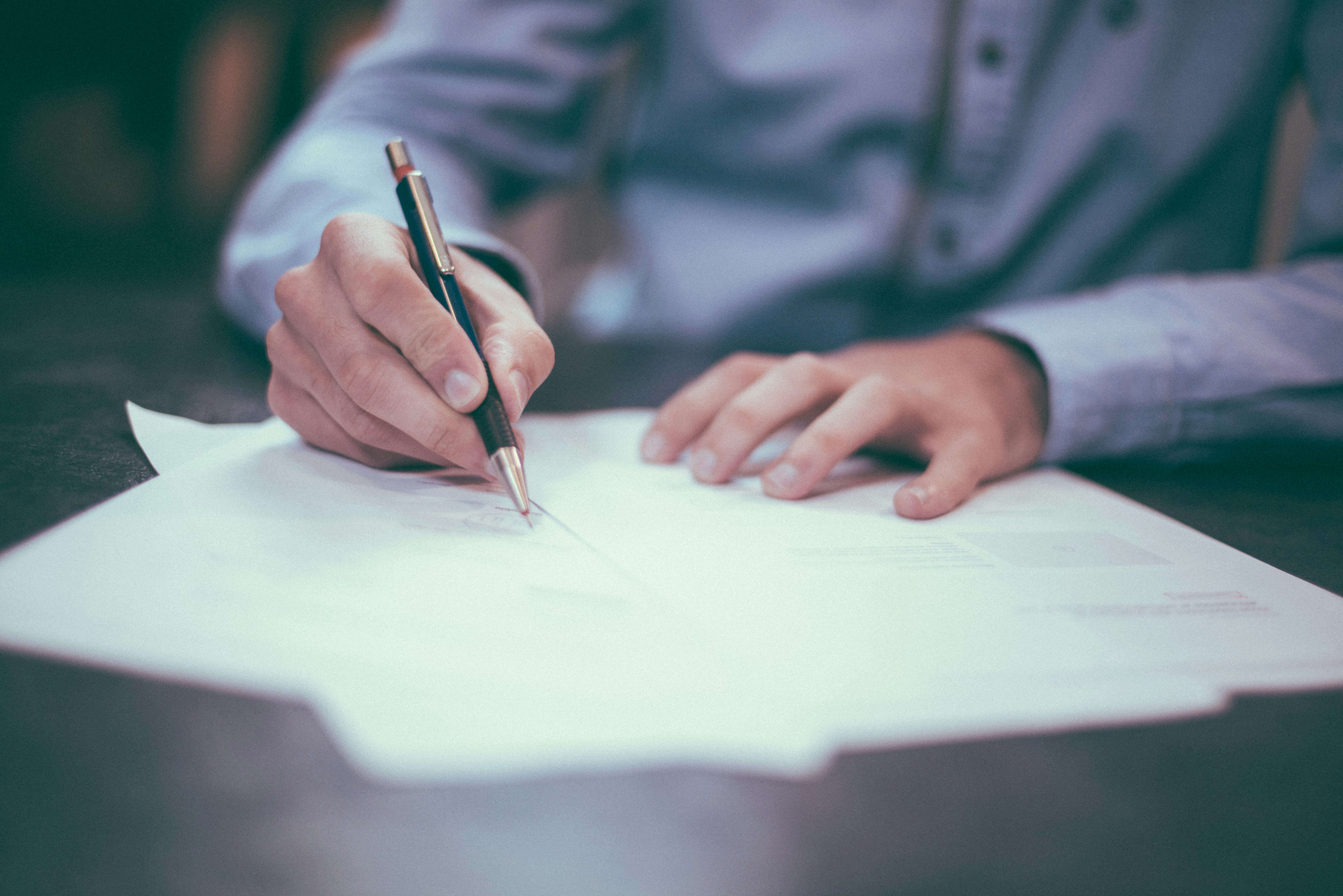 Close-up of a person signing a document, representing mortgage application and closing paperwork.