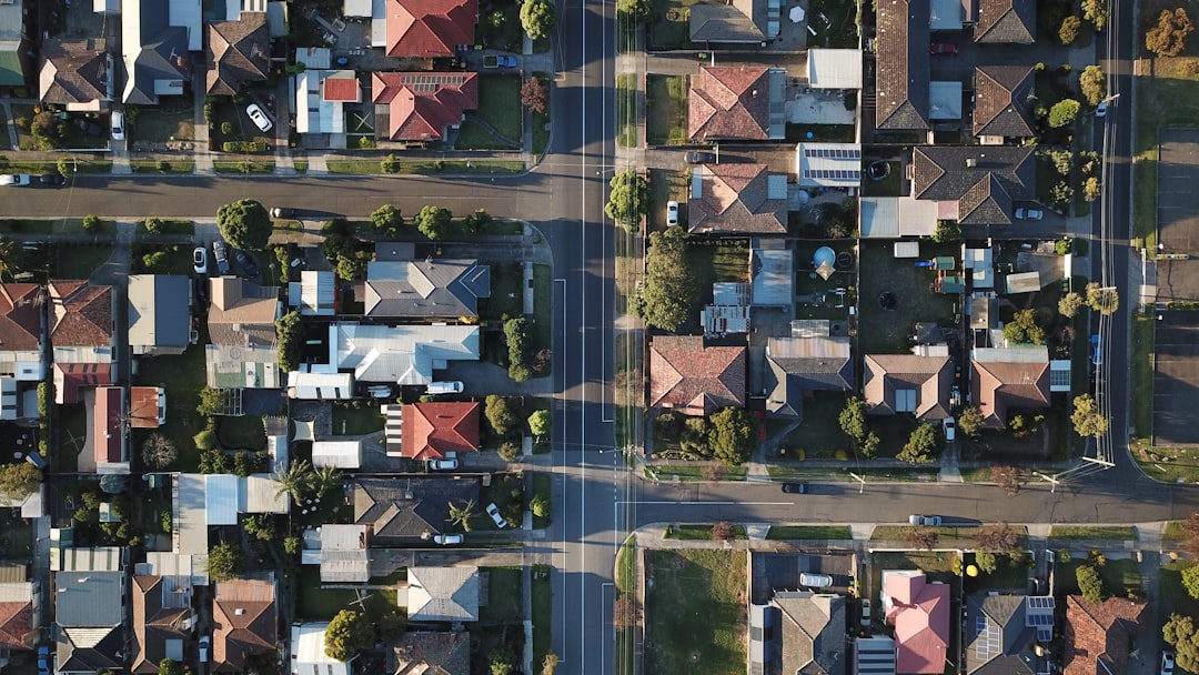 Drone view of a residential neighborhood with homes, intersections, and tree-lined streets.