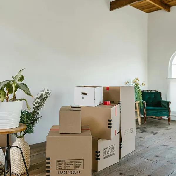 Moving boxes stacked on a wooden floor in a room with exposed beams.