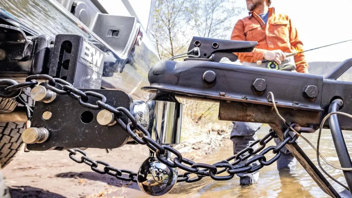 Man carefully attaching a trailer hitch to a vehicle, ensuring a secure and proper connection