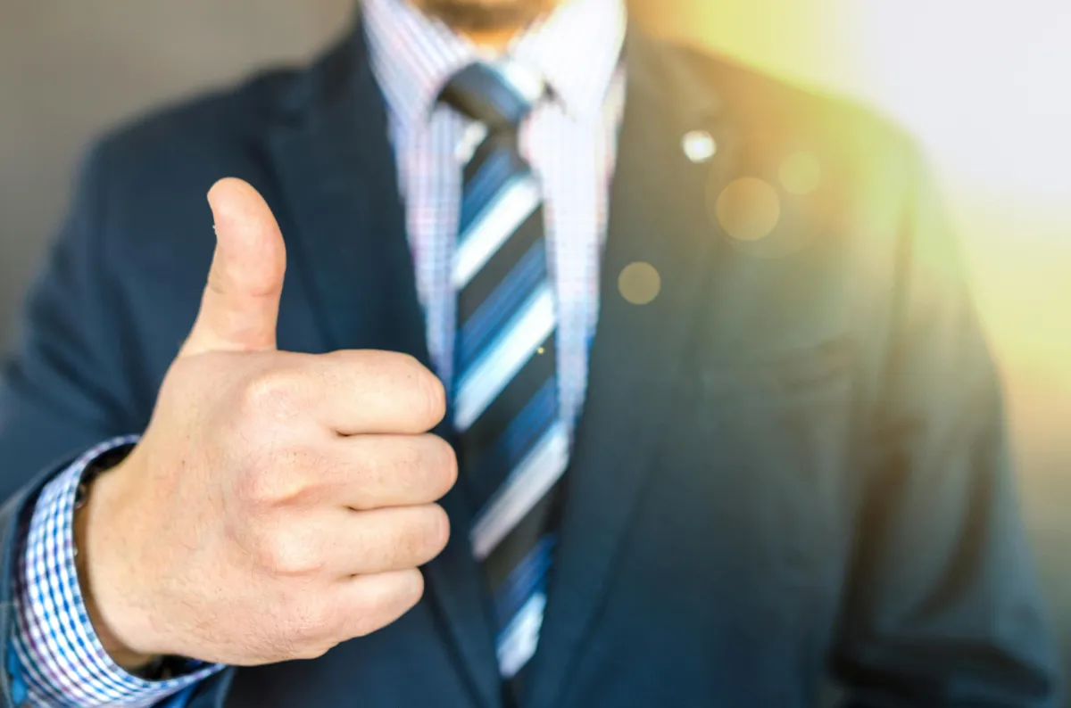 man in suit doing an okay sign on their hand