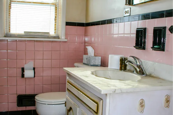 small bathroom with fiberglass tub/shower combo and dated/old pink tile