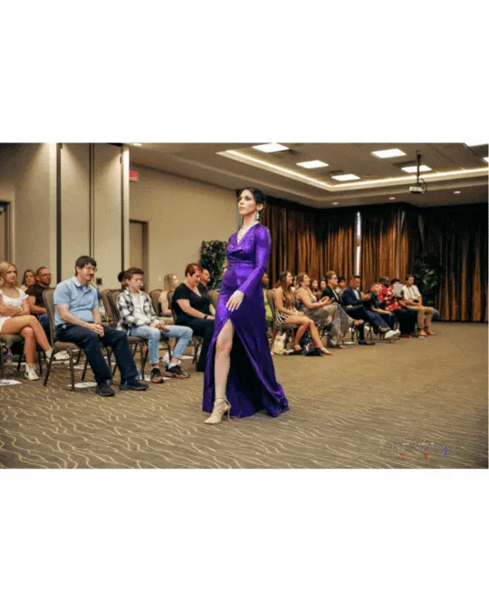 Crystal Roman modeling a purple gown on the runway.