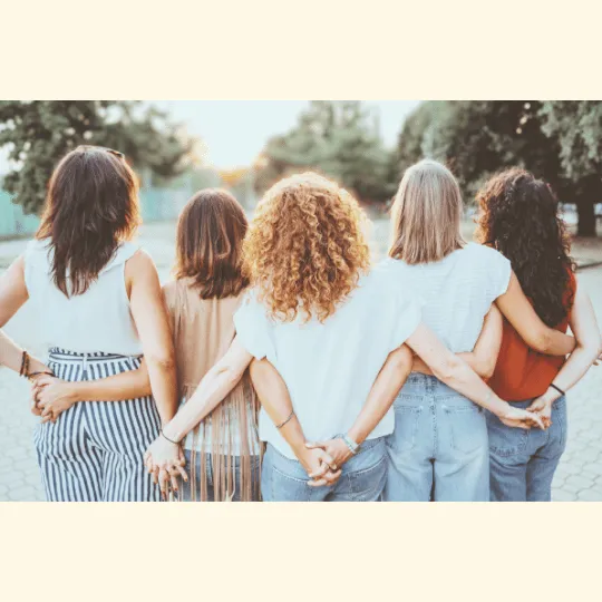 Group of women embracing outdoors, representing trauma-informed sisterhood and emotional healing.