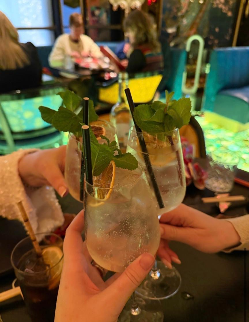 Cocktails raised in a toast during the Beauty & Theory Christmas night out at Ivy Asia, featuring festive drinks in a vibrant restaurant setting.