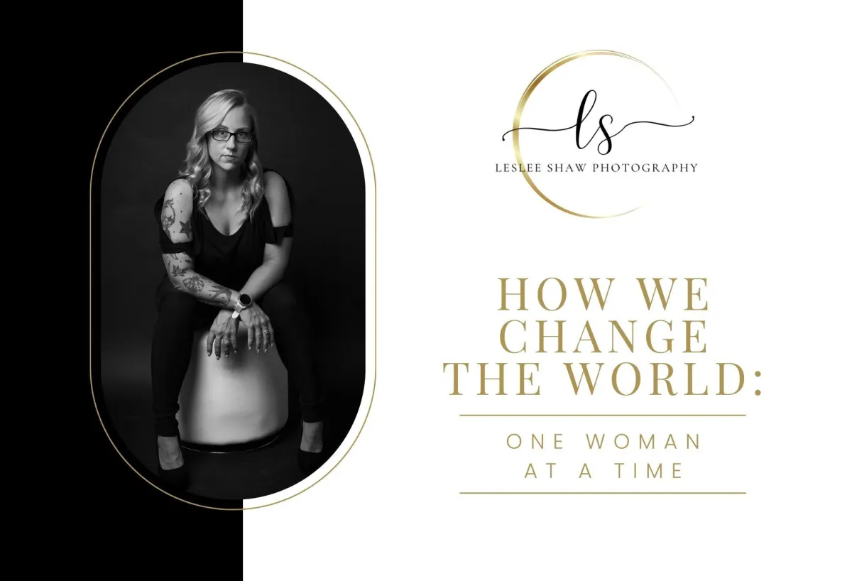 Monochrome portrait of a blonde, tattooed woman seated on a stool wearing glasses, next to the Leslee Shaw Photography logo and the text ‘How We Change the World: One Woman at a Time.’