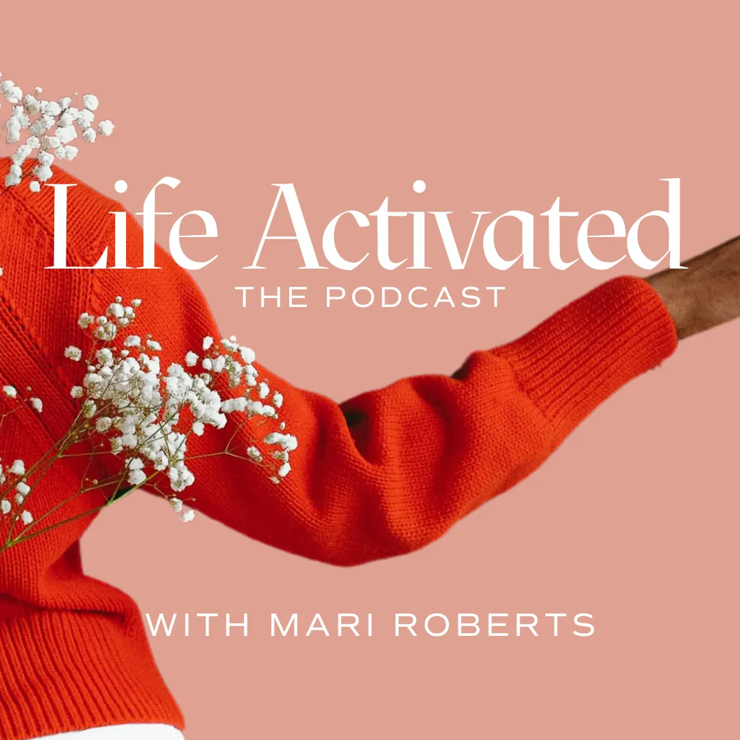 Arm of a woman in a red sweater with white flowers and a pink background