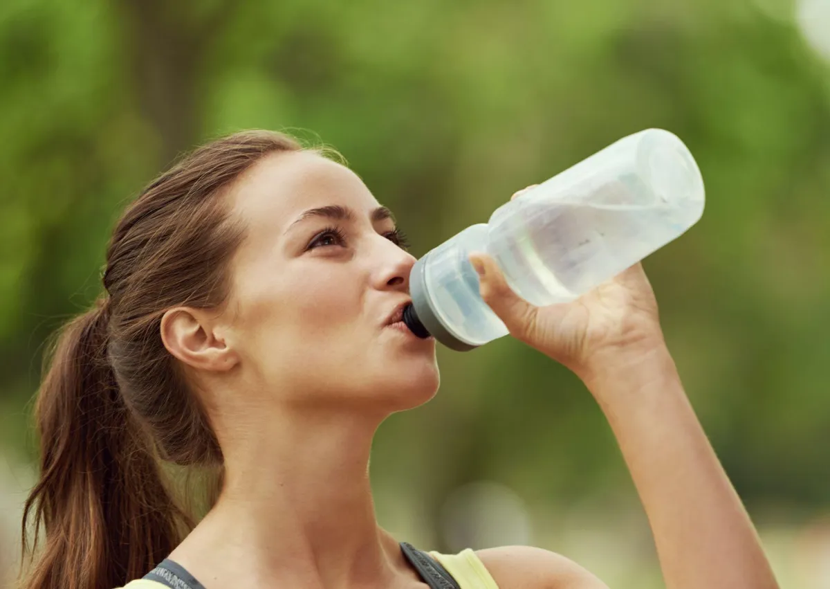 Smiling woman drinking water to stay hydrated and healthy