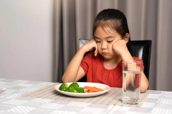 Ayoung girl looking unhappy at her food