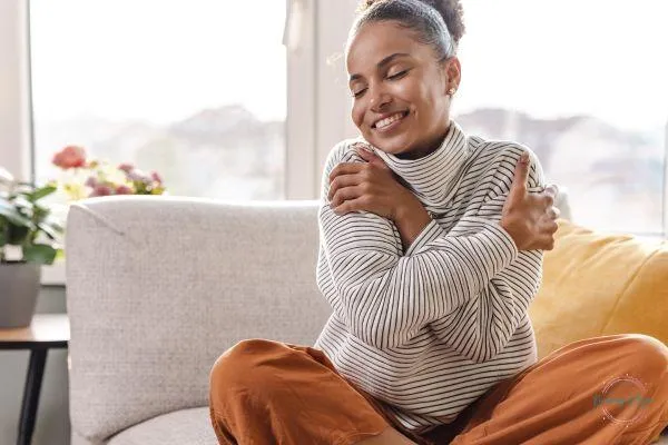 Woman wrapping her arms around herself with her eyes closed