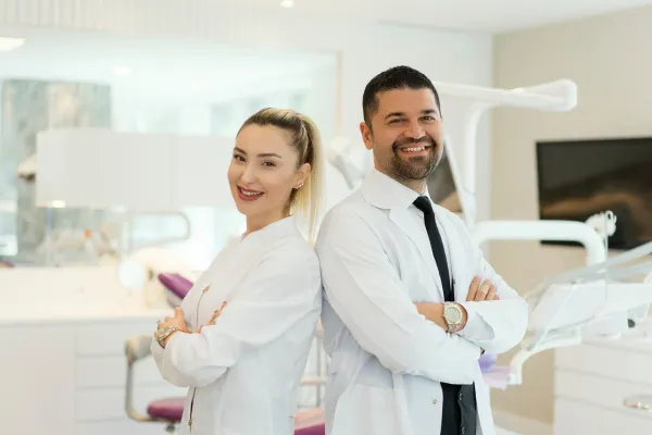 Two dentists smiling standing in dentist office