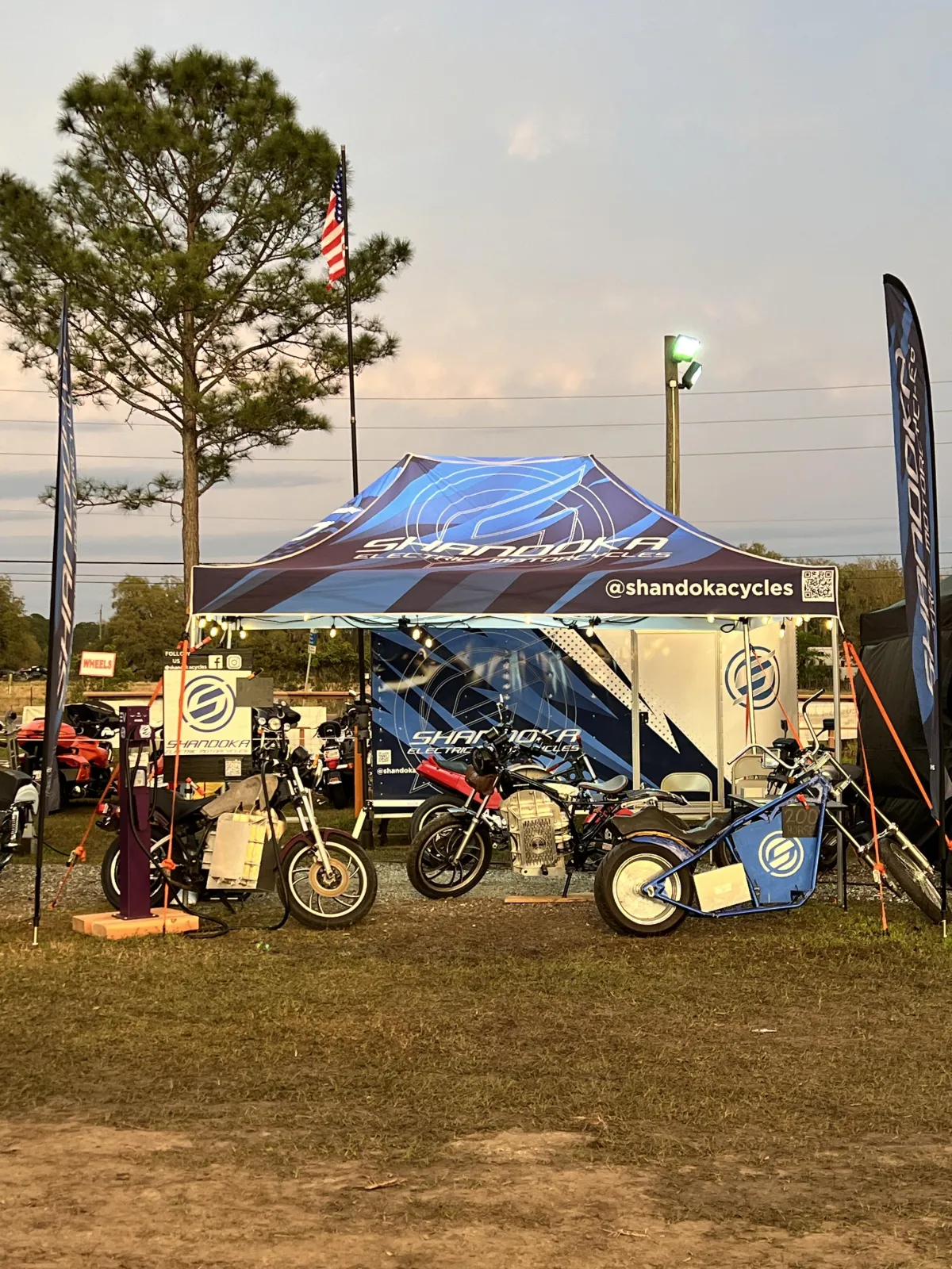 Sunset View of Vending tent with motorcycles, American Flag flys above it.