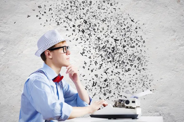 Man, wearing a top hat and bowtie, sitting at a typewriter pondering what to write with letters floating into the air – image represents how to write compelling social media content.