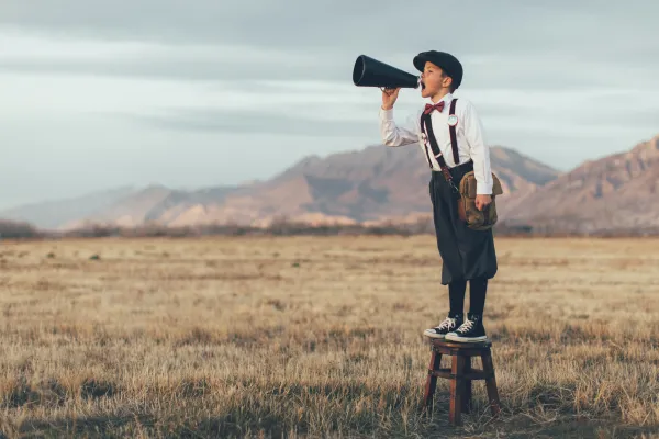 A boy dressed in an old-fashioned outfit, standing on a stool with a megaphone shouting – represents how owners can promote their businesses for free.
