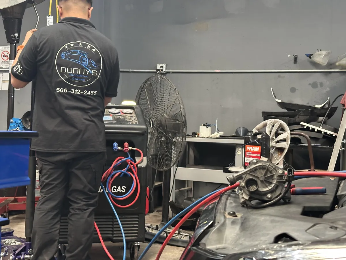 “ASE certified technician at Donny’s Automotive inspecting a car engine for summer maintenance, checking fluid levels and hoses.”