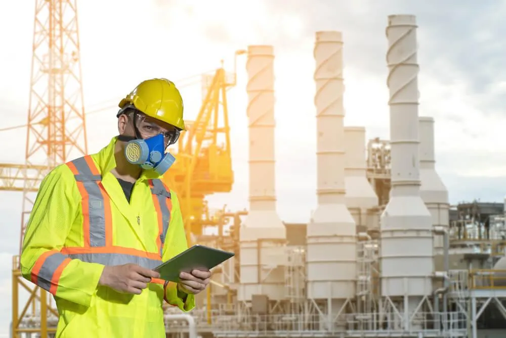 A worker wearing a yellow helmet and suit, and a respiratory protection