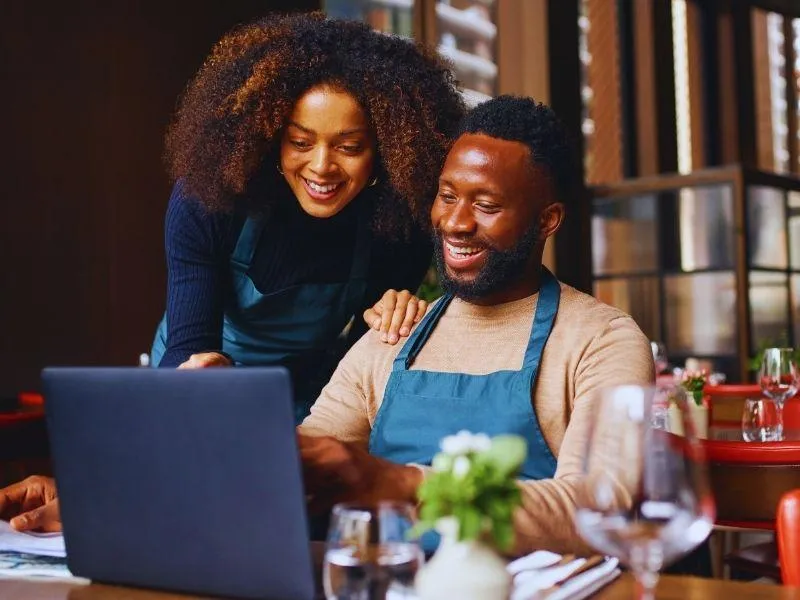 Smiling Business Owners Working on Laptop