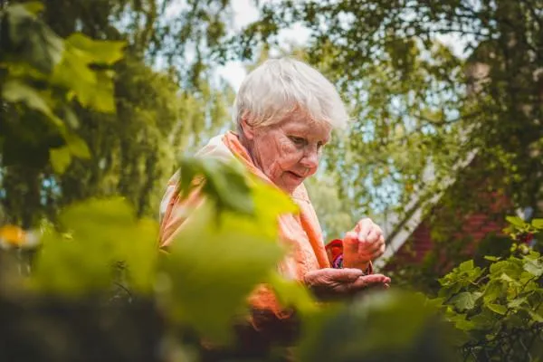 A senior woman tending to her garden smiling.