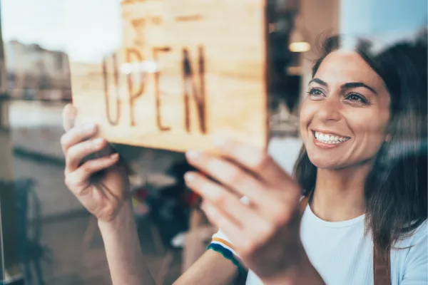 Small business owner holding Open signage