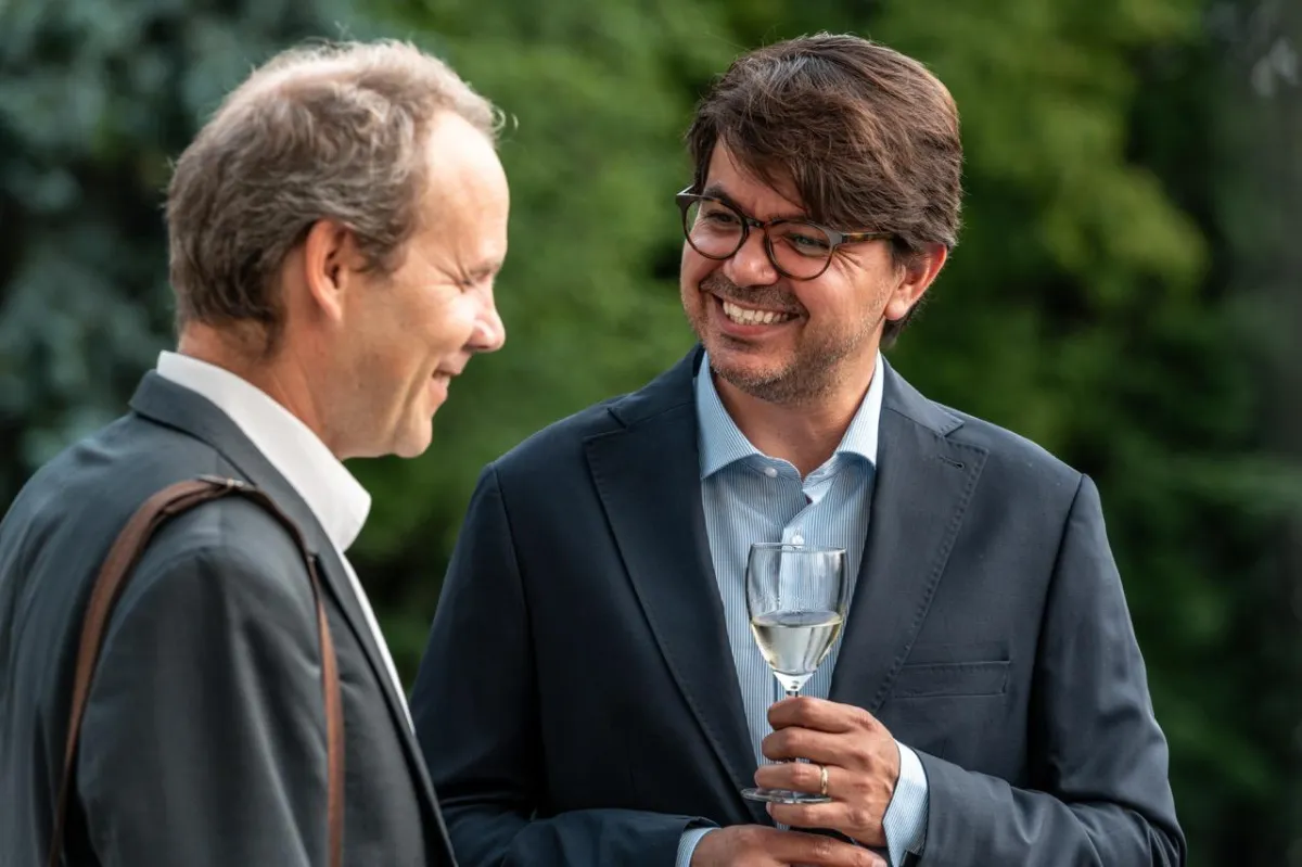 Two delegates smiling during a conversation in the garden of the UK Ambassador's residence, Oslo