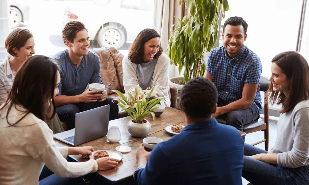 A group of people sitting around a table, having an engaging conversation, promoting collaboration and social connection.