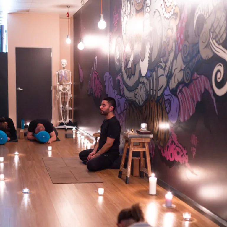 Practitioner relaxing in Reclining Hero Pose (Supta Virasana) with the back supported by bolsters, opening the front body and encouraging deep rest.