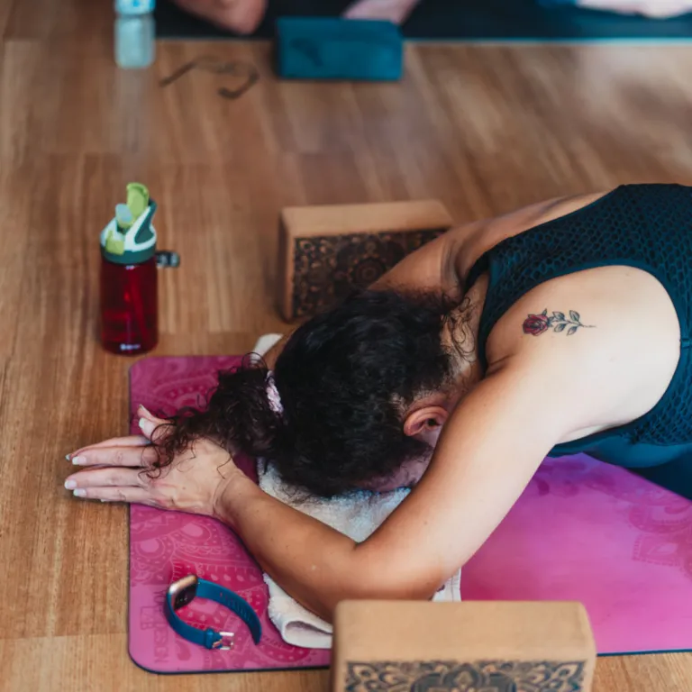 Person in a peaceful seated yoga pose with eyes closed and hands resting on knees, breathing calmly to represent intention, clarity, and inner focus.