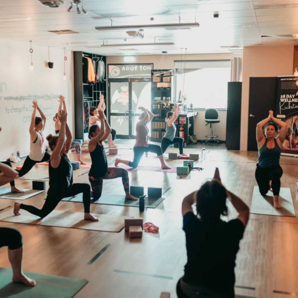 Person practising Kneeling Crescent Lunge with front knee bent, back knee on the mat, hips gently pressing forward, and arms reaching overhead on a yoga mat.