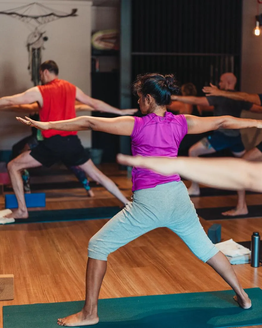 Practitioner in Warrior II Pose (Virabhadrasana II) with front knee bent, arms extended, hips open, and gaze over the front hand, building strength and focus.