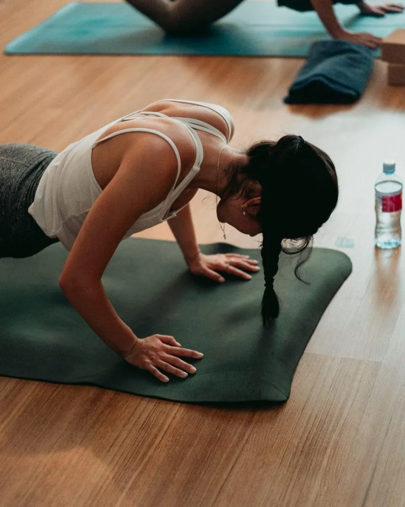 Person holding Stacked Plank Pose with one foot stacked on the other, arms straight, core engaged, and body in a strong line on a yoga mat.