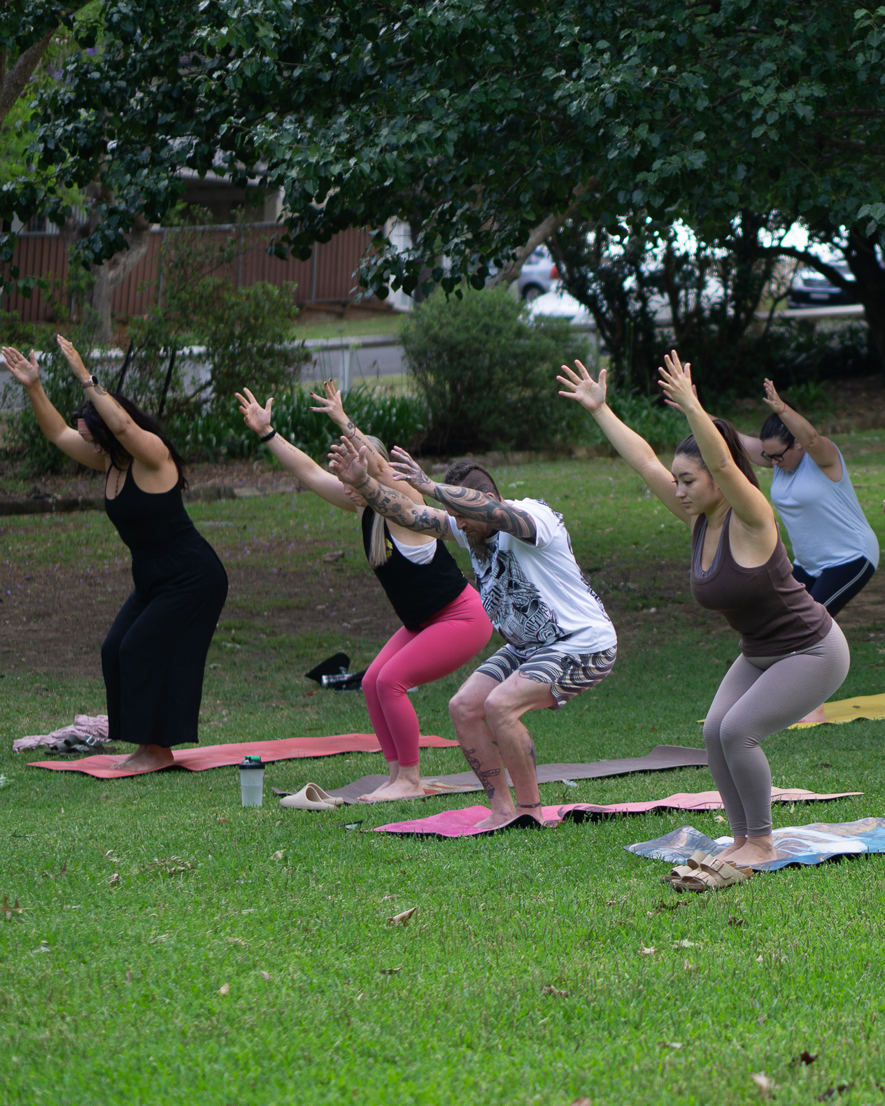 People practicing yoga in a park at sunrise, surrounded by trees and sunlight — representing the calming and restorative power of outdoor activities for mental health.