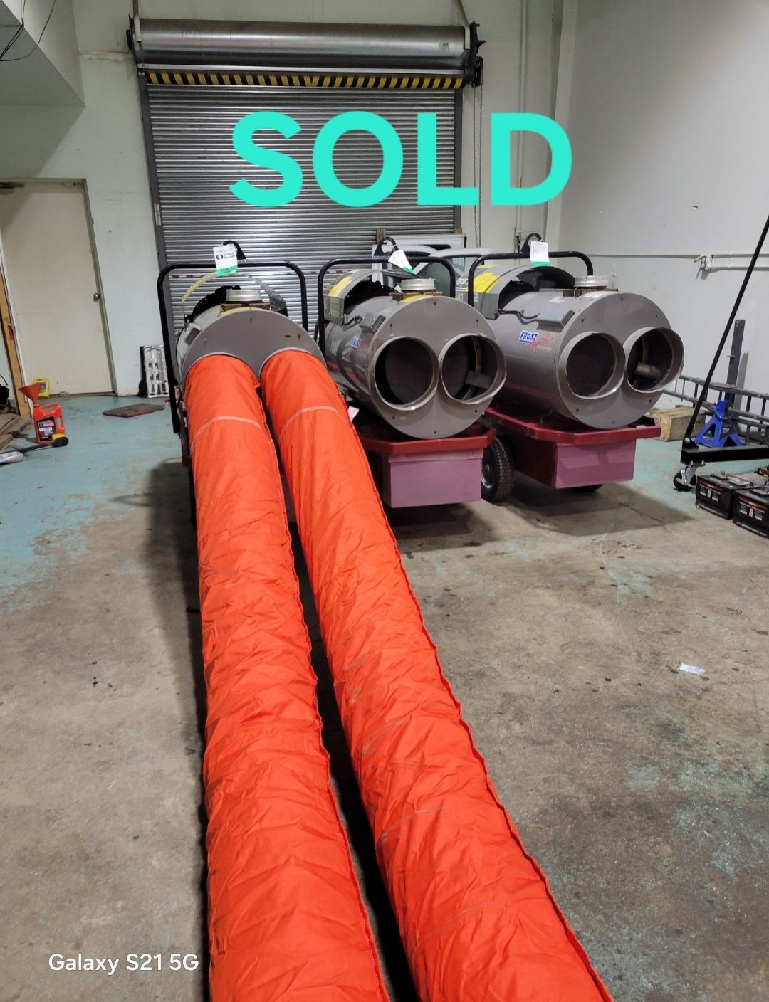 Multiple Frost Fighter 350,000 BTU diesel heaters with red ducting socks in warehouse facility
