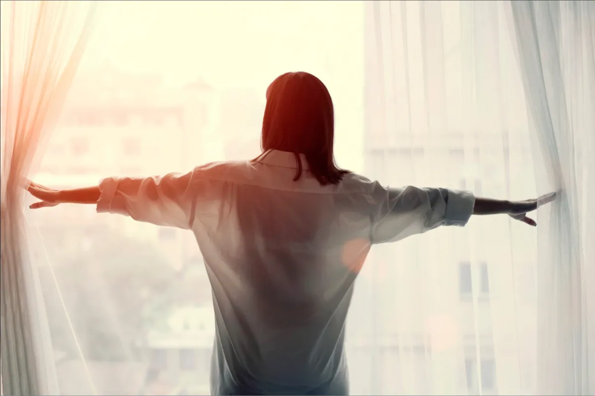 Woman at window with sunlight pouring through