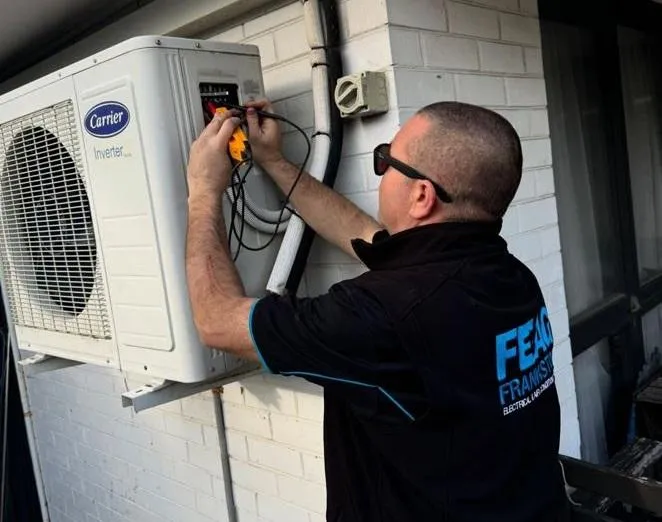 "Professional Frankston electrician installing an energy-efficient air conditioning unit for a comfortable home, featuring expert service and support with Victorian Government rebate incentives."