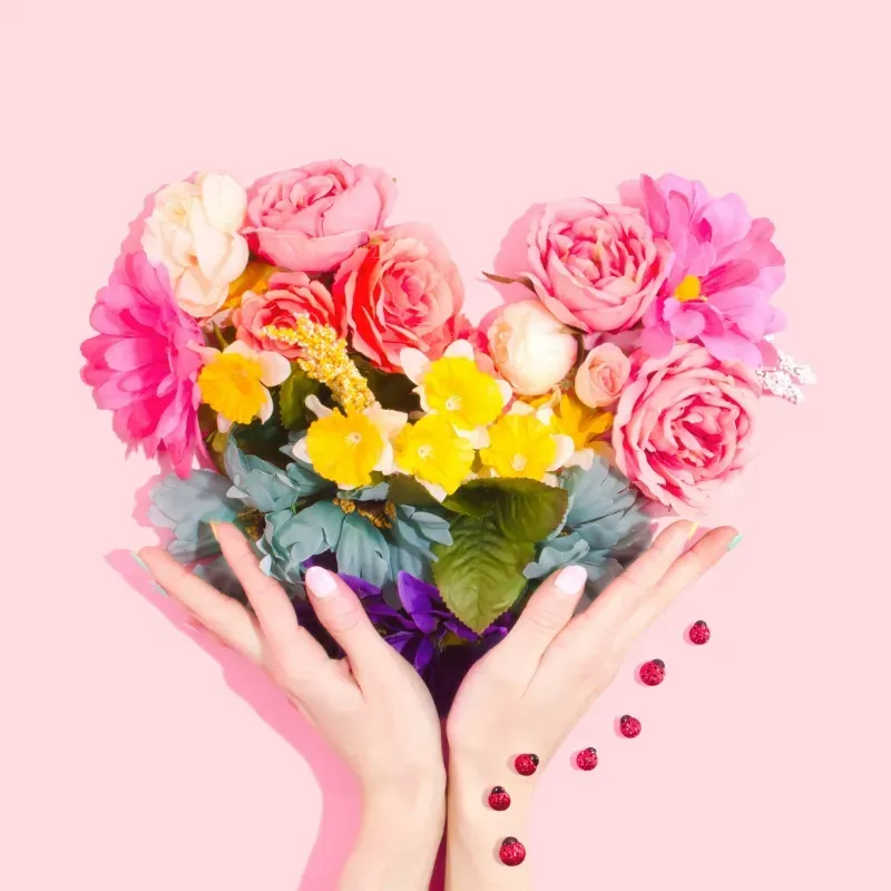two hands holding a heart-shaped bouquet of flowers