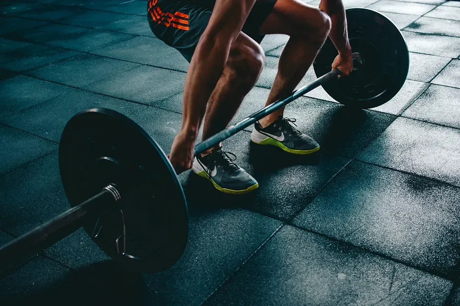 Male bent over to lift barbells