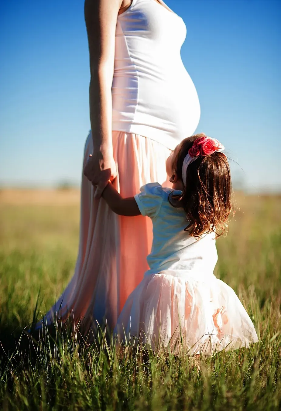 pregnant woman holding hand of a toddler