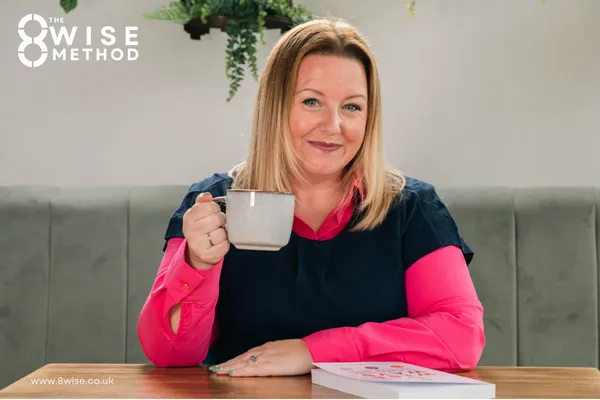 Kim Rutherford smiling to the camera holding a cup of tea