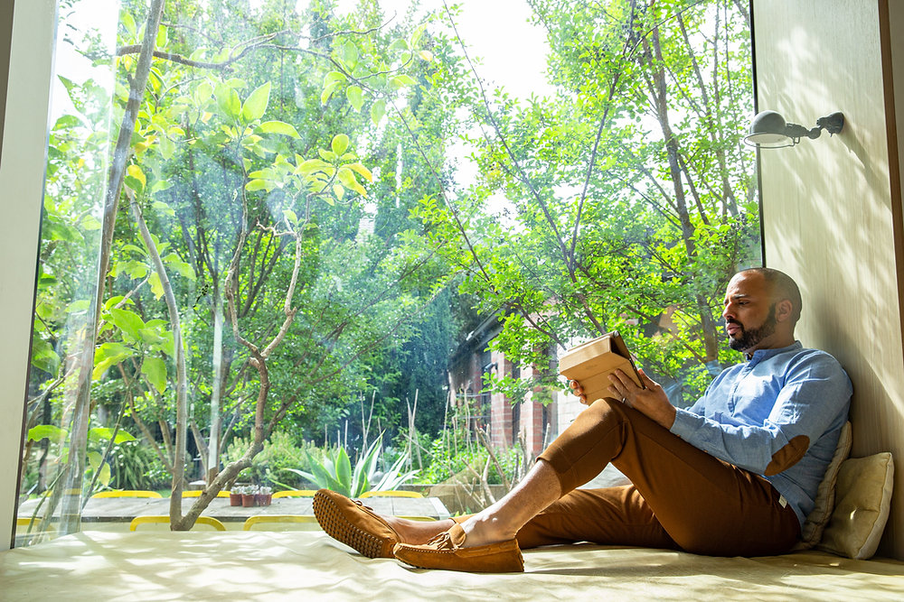Man sitting in a bright room with a window showing wooded yard