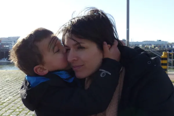 a child kissing his tired mum on a cheek