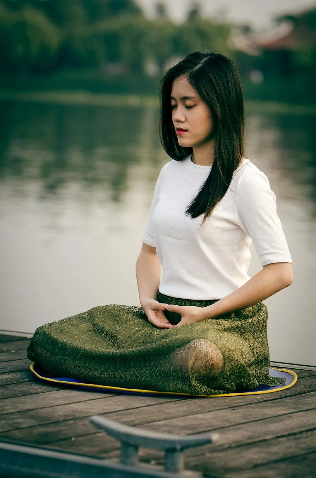Woman meditating in nature next to calm water