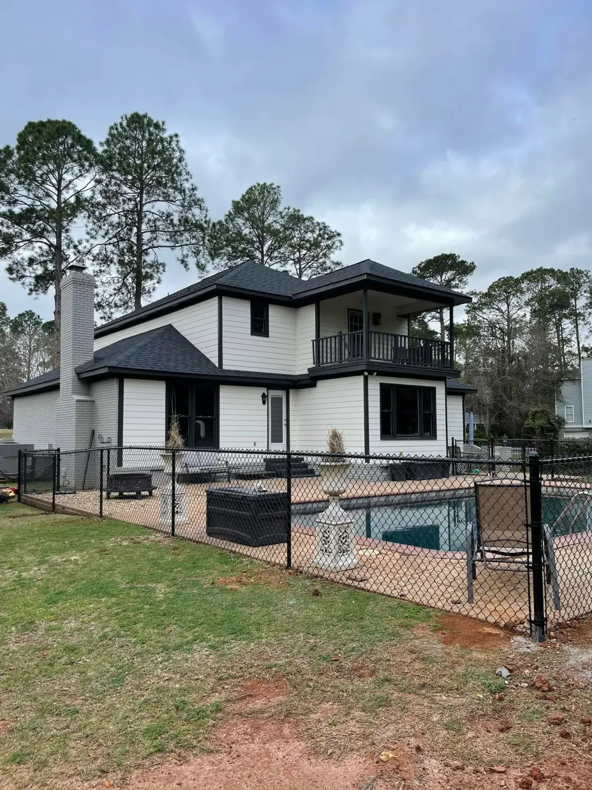Black chain link fence surrounding a residential pool and modern home, a safety and boundary solution by MCM Fence LLC in Georgia.