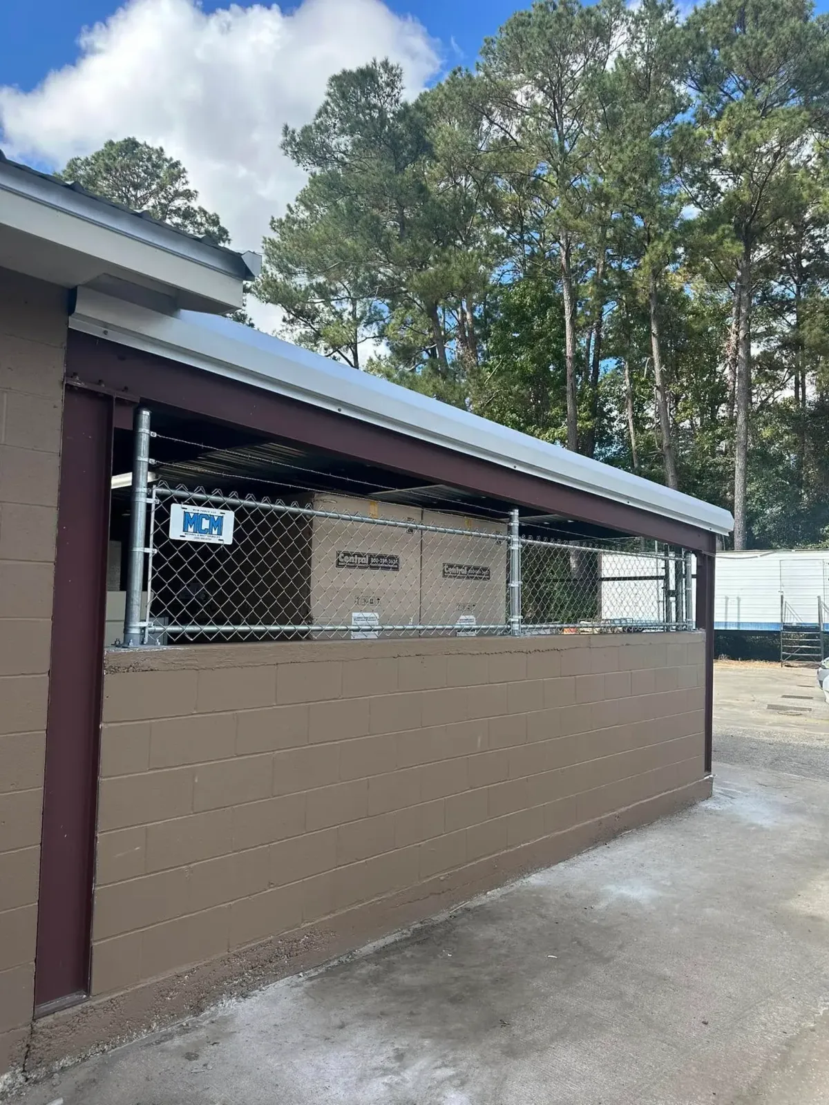 Custom chain link security enclosure with MCM Fence LLC logo, providing secure storage for commercial equipment in Georgia.