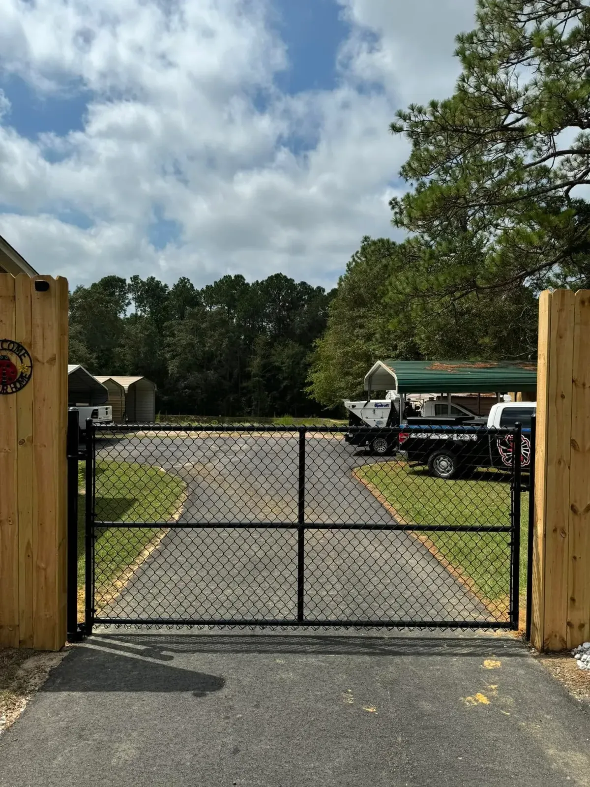 Black chain link driveway gate with wooden accent posts, installed by MCM Fence LLC for a residential property in Georgia.