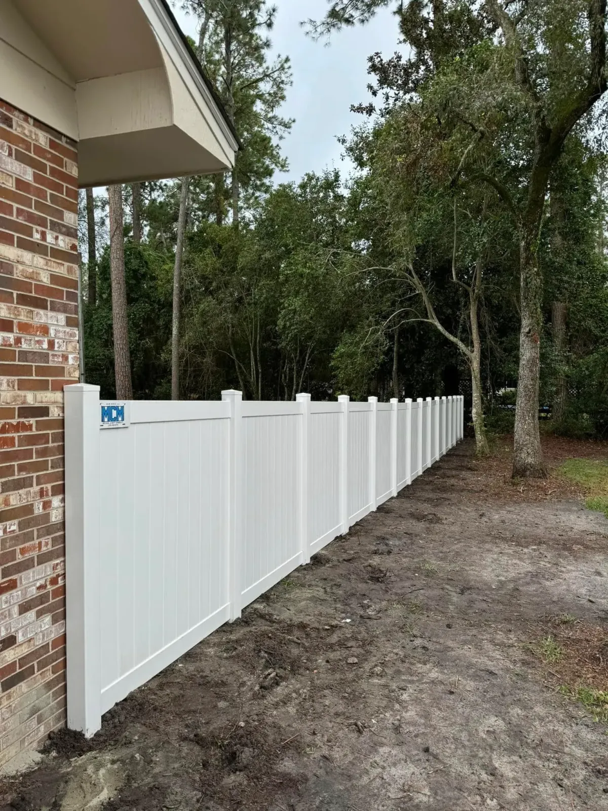 Clean white vinyl privacy fence installation alongside a brick home by MCM Fence LLC, enhancing backyard privacy in Georgia.