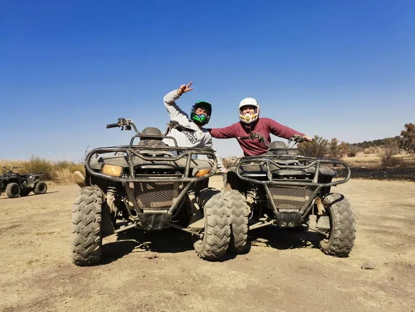 Two riders pose on their ATVs in an open dirt field under a clear blue sky, symbolizing street-legal ATV riding in Florida.