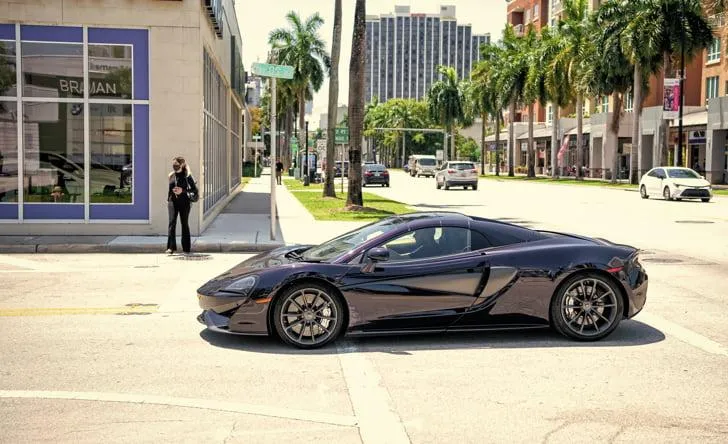 Black sports car on Illinois street — realistic photo representing how much it costs to transfer a car title in Illinois.