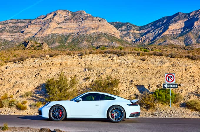 White Porsche parked on a scenic Arkansas road, with a sign indicating one-way traffic, symbolizing a car title transfer in Arkansas.